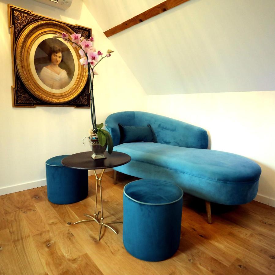 Coin salon avec canapé de velours bleu sous un portrait ancien