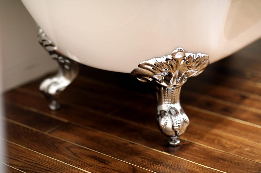 Détail des pieds chromés d'une baignoire sur parquet